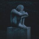 sculpture of man holding knees and crying